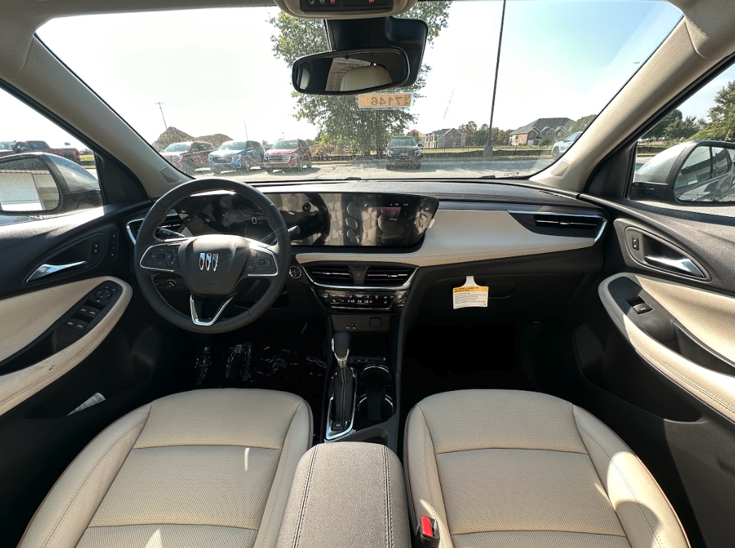 Interior view of a new Buick with beige seats and digital display, parked at Crain Buick GMC in Springdale